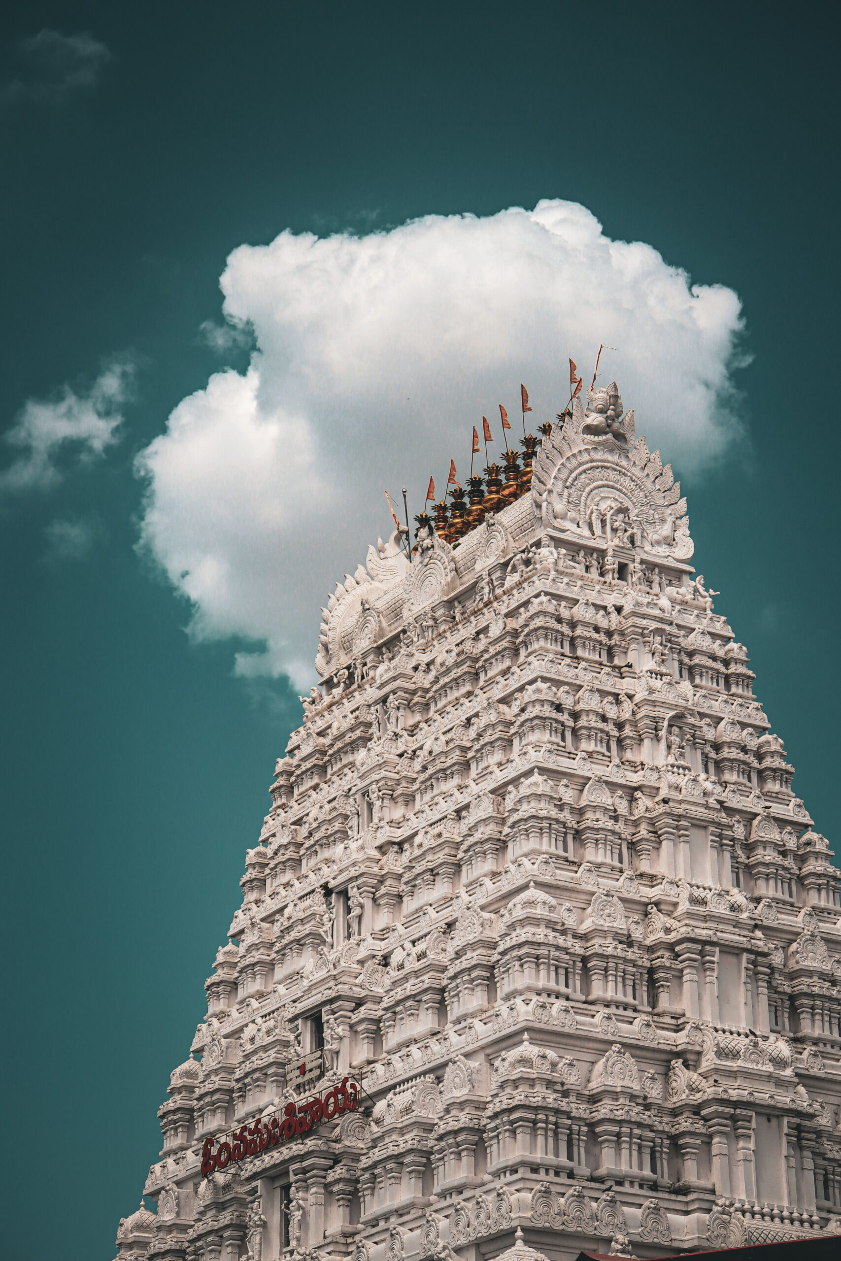 Intricate architecture of a Gopuram in India under a dramatic sky, showcasing cultural heritage.